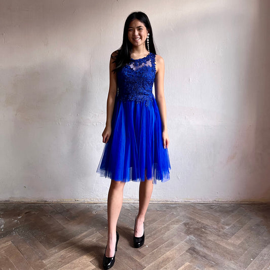 Modelka asijského původu pózující zepředu oblečená ve krátkých královsky modrých společenských šatech 