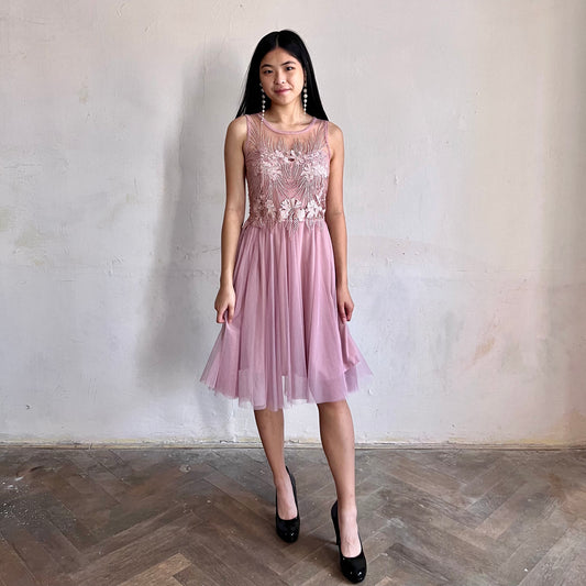 Modelka asijského původu pózující zepředu oblečená ve krátkých krajkovaných růžových společenských šatech