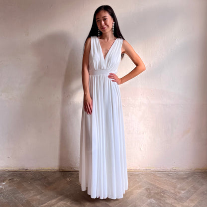 Modelka asijského původu pózující zepředu oblečená ve dlouhých bílých společenských šatech