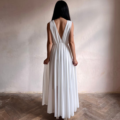 Modelka asijského původu pózující zezadu oblečená ve dlouhých bílých společenských šatech