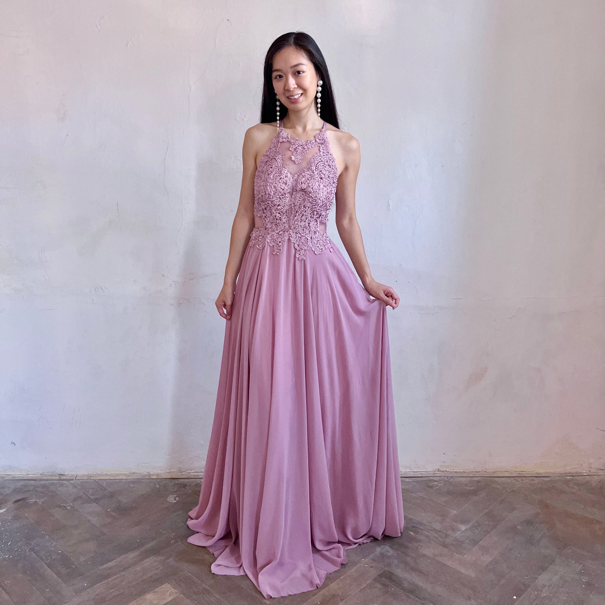 Modelka asijského původu pózující zepředu oblečená ve starorůžových krajovaných společenských šatech