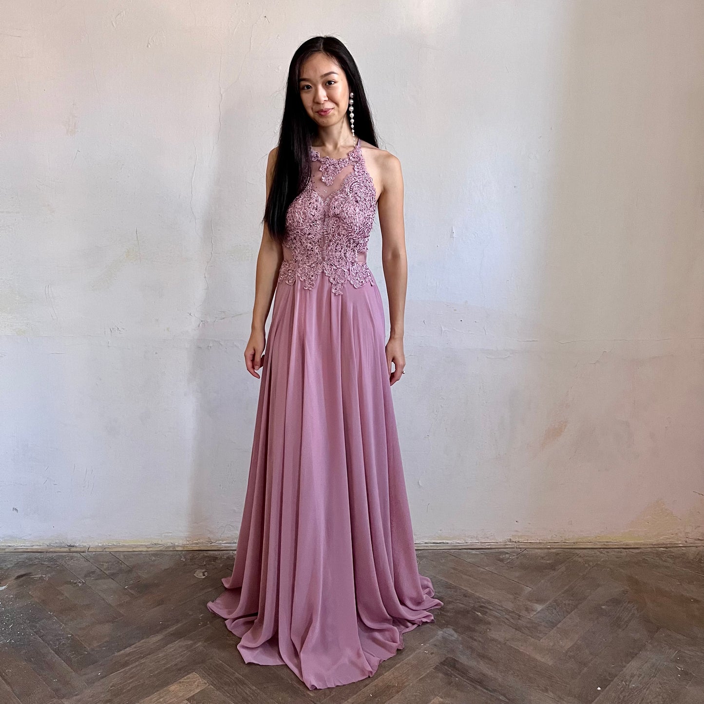 Modelka asijského původu pózující zepředu oblečená ve starorůžových krajovaných společenských šatech