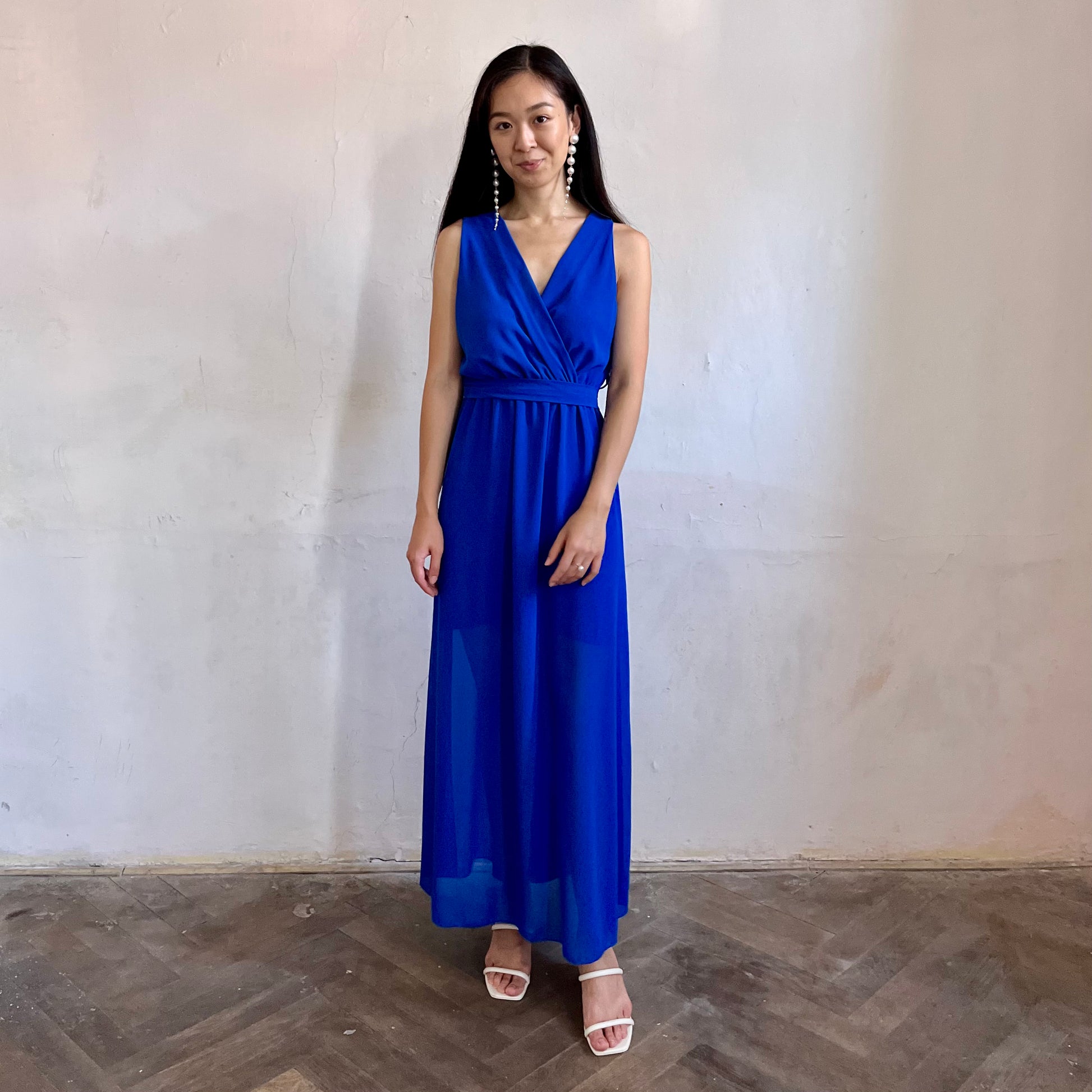 Modelka asijského původu pózující zepředu oblečená ve královsky modrých společenských šatech