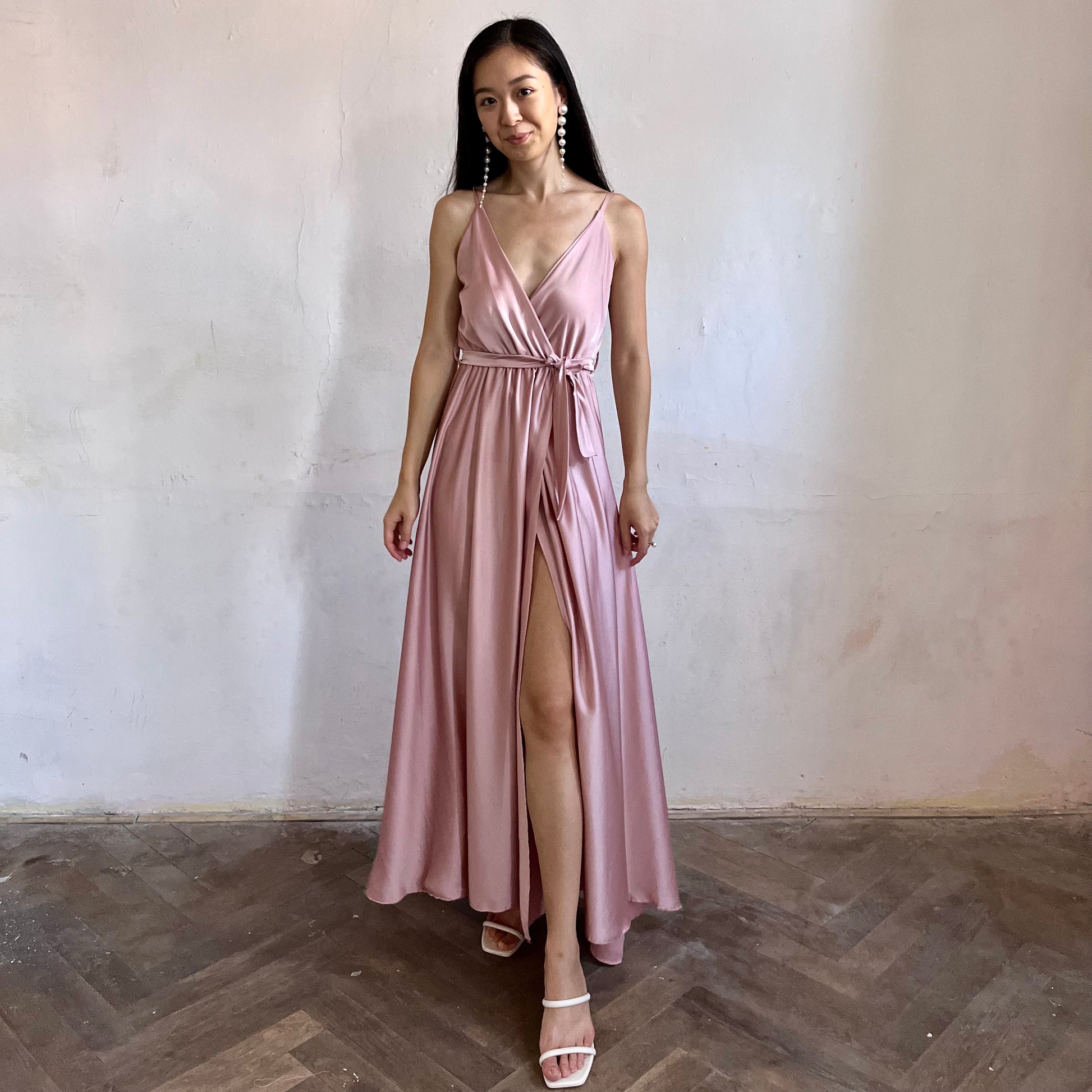 Modelka asijského původu pózující zezadu oblečená ve světle růžových společenských šatech