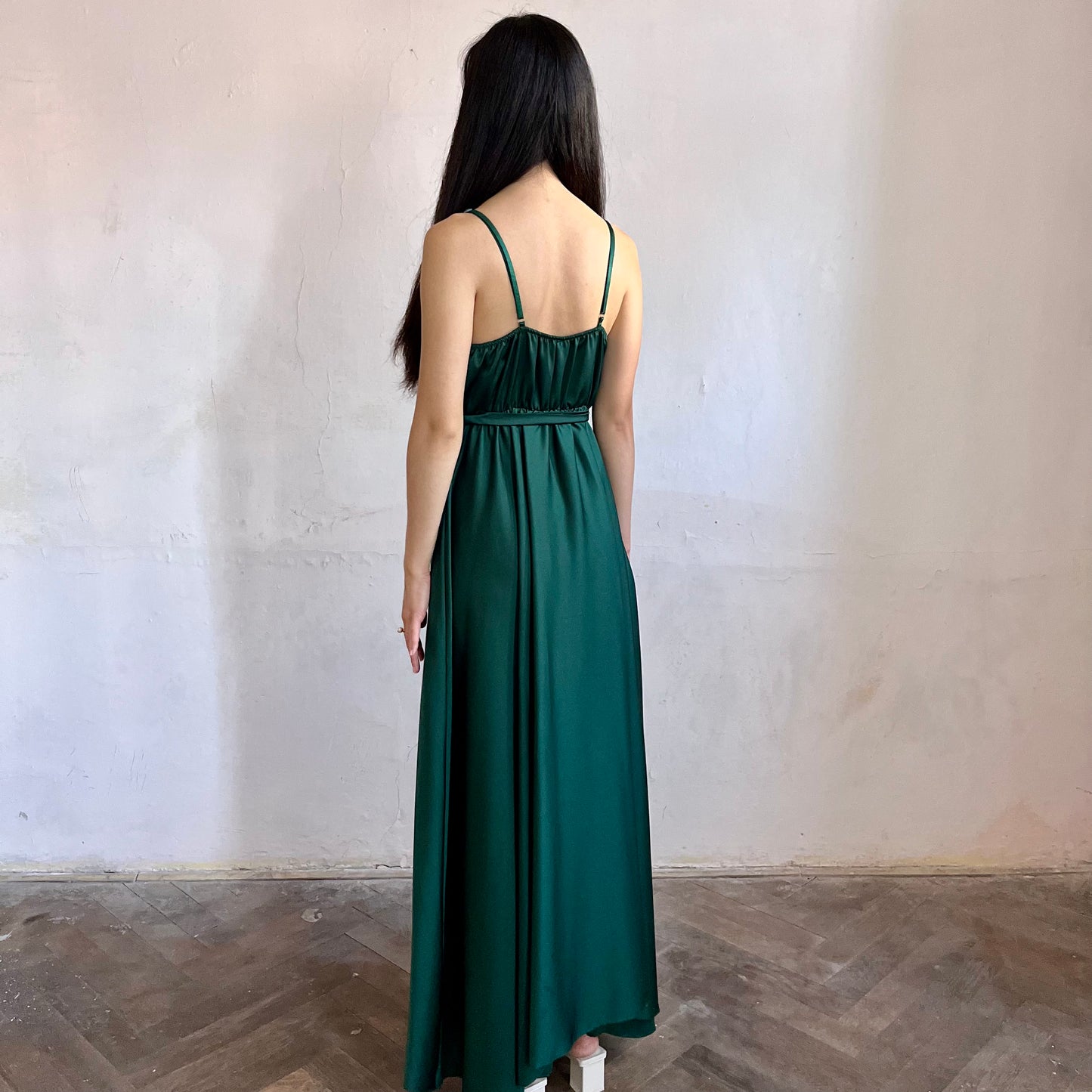 Modelka asijského původu pózující z boku oblečená v tmavě zelených společenských šatech