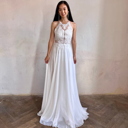Modelka asijského původu pózující zepředu oblečená v bílých krajkovaných společenských šatech