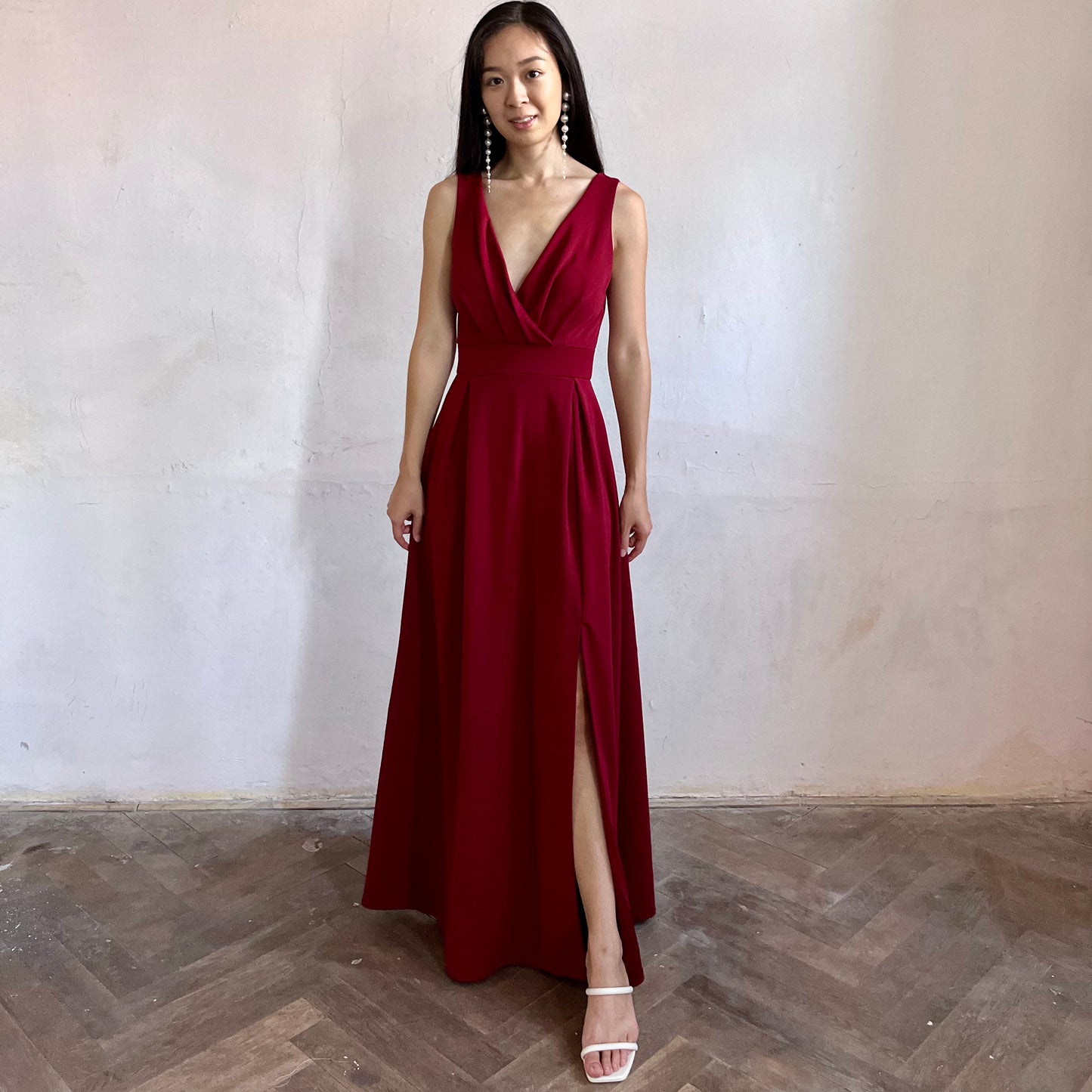 Modelka asijského původu pózující zepředu oblečená v tmavě vínových společenských šatech