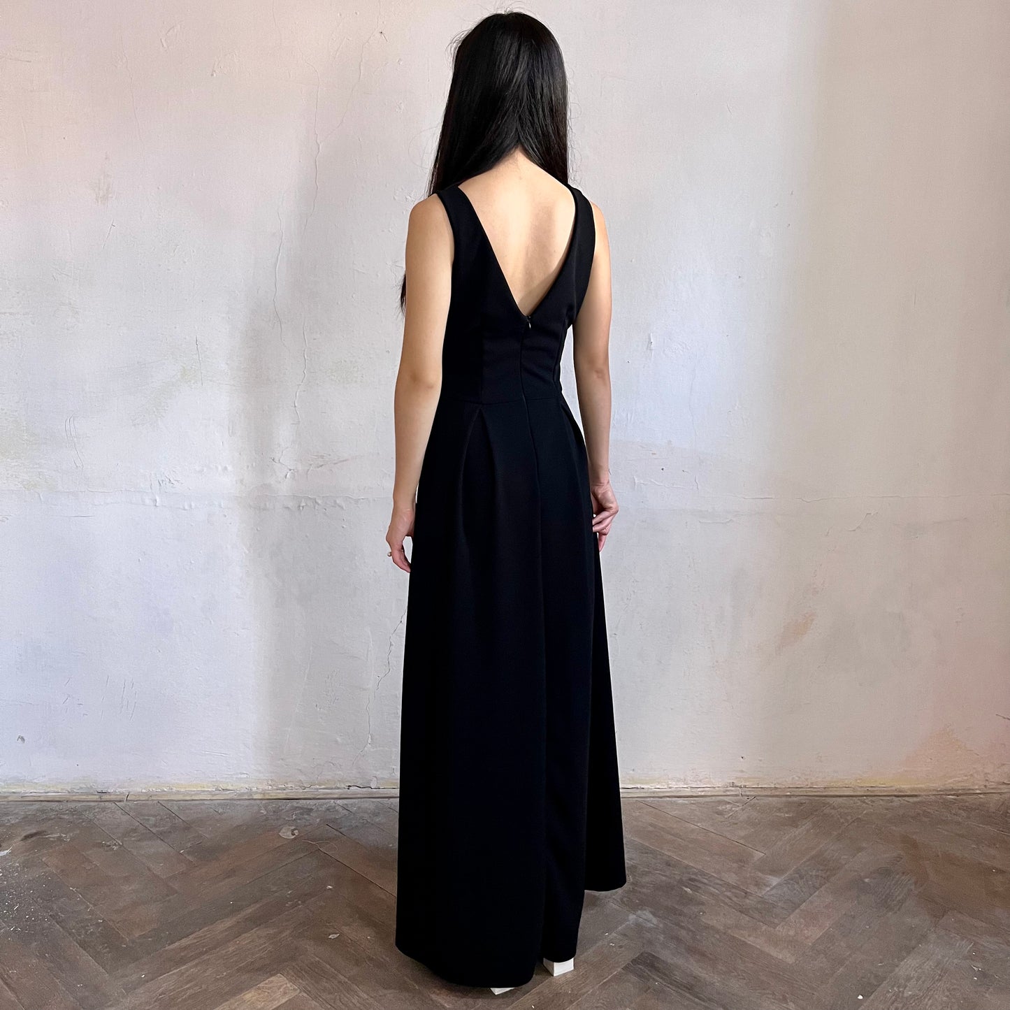 Modelka asijského původu pózující zezadu oblečená v černých společenských šatech