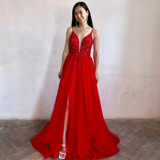 Modelka asijského původu pózující zepředu oblečená v červených třpytivých společenských šatech