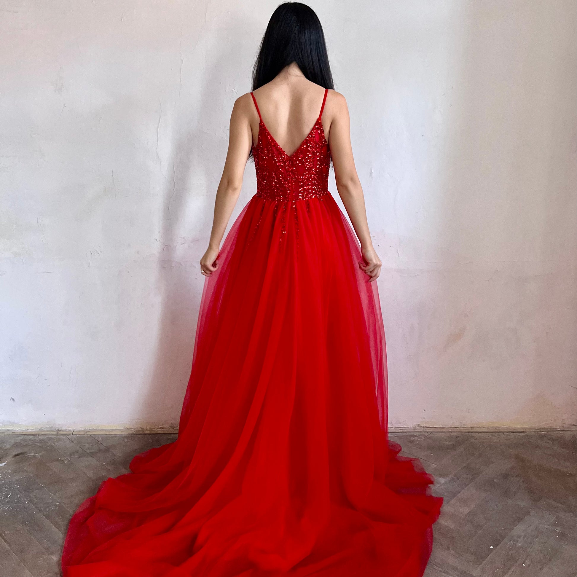 Modelka asijského původu pózující zezadu oblečená v červených třpytivých společenských šatech