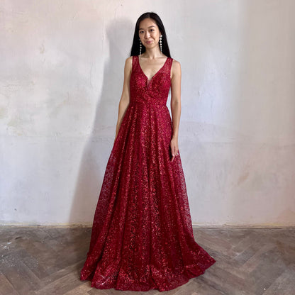 Modelka asijského původu pózující zepředu oblečená ve vínových třpytivých společenských šatech