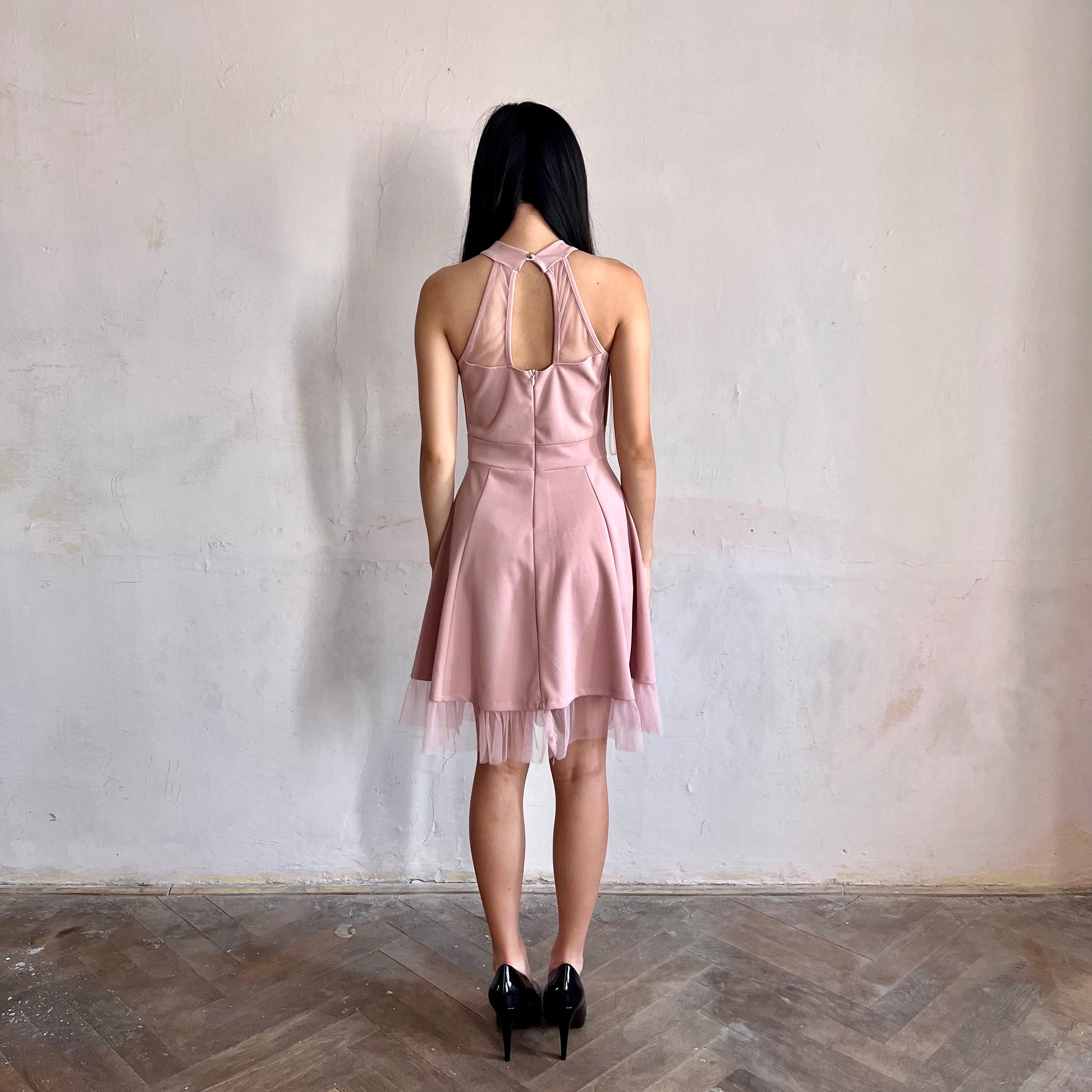 Modelka asijského původu pózující zezadu oblečená v růžových krátkých společenských šatech