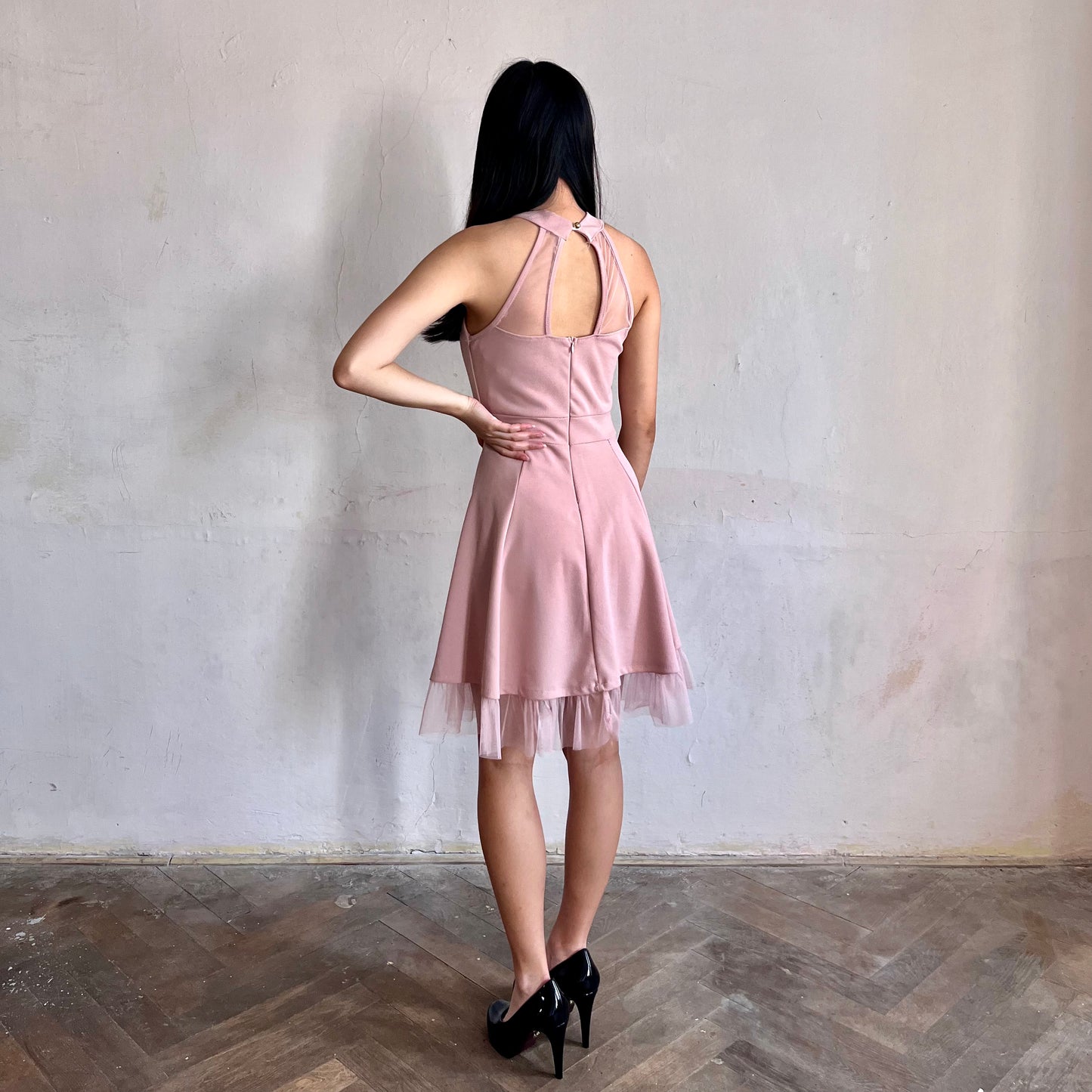 Modelka asijského původu pózující z boku oblečená v růžových krátkých společenských šatech