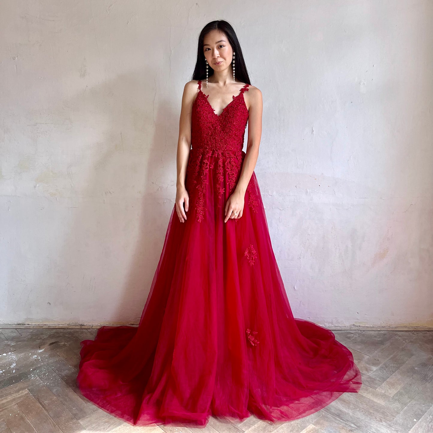 Modelka asijského původu pózující zepředu oblečená v dlouhých červených třpytivých plesových šatech 