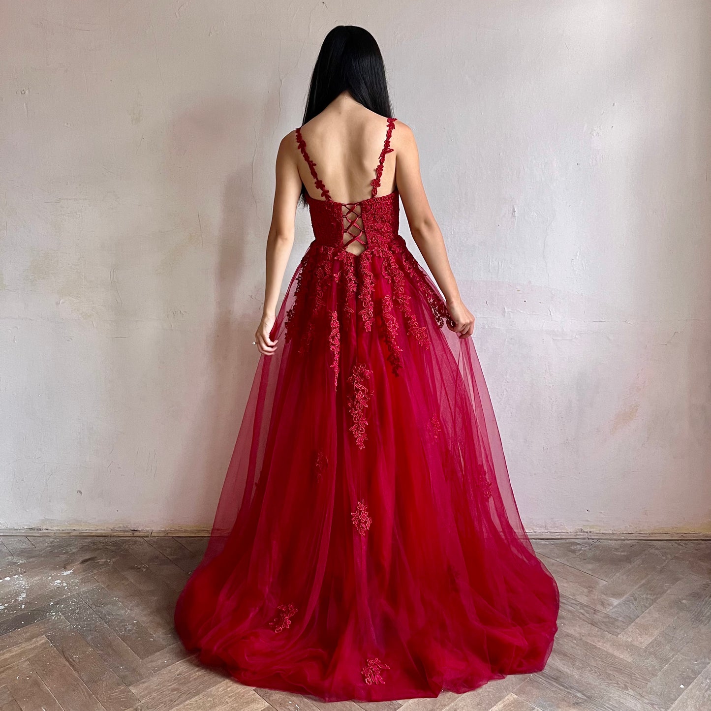 Modelka asijského původu pózující zezadu oblečená v dlouhých červených třpytivých plesových šatech 