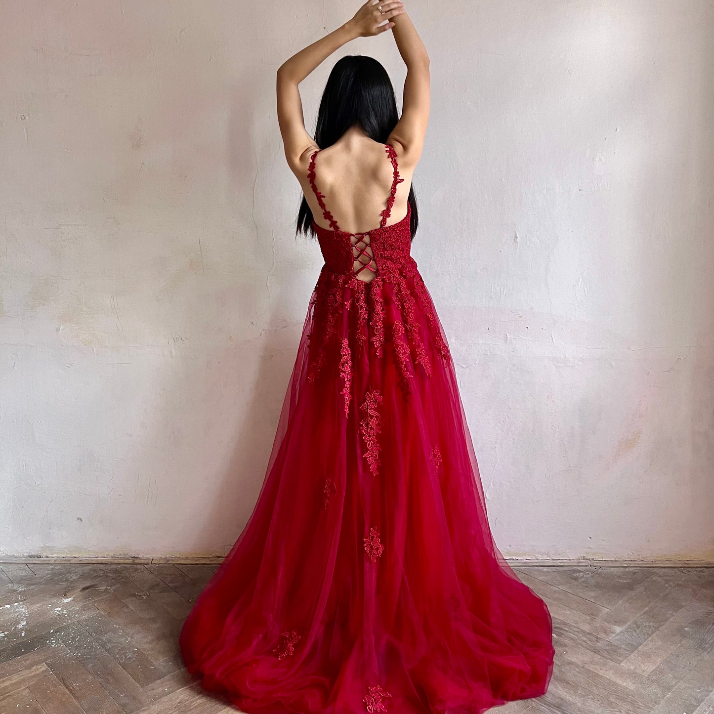 Modelka asijského původu pózující zezadu oblečená v dlouhých červených třpytivých plesových šatech 
