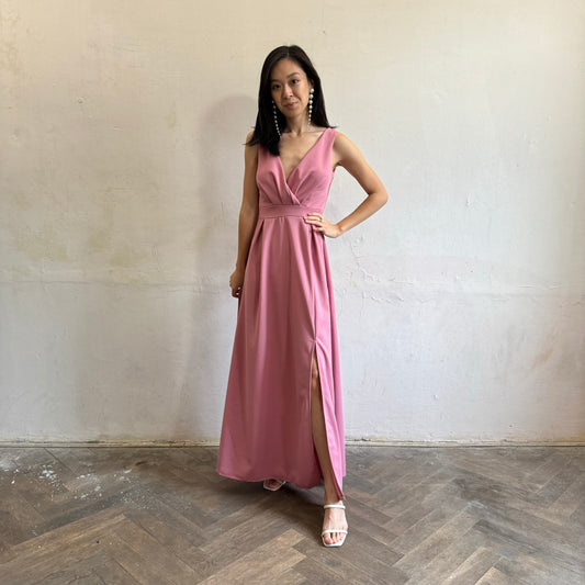Modelka asijského původu pózující zepředu oblečená ve tmavě růžových společenských šatech s rozparkem