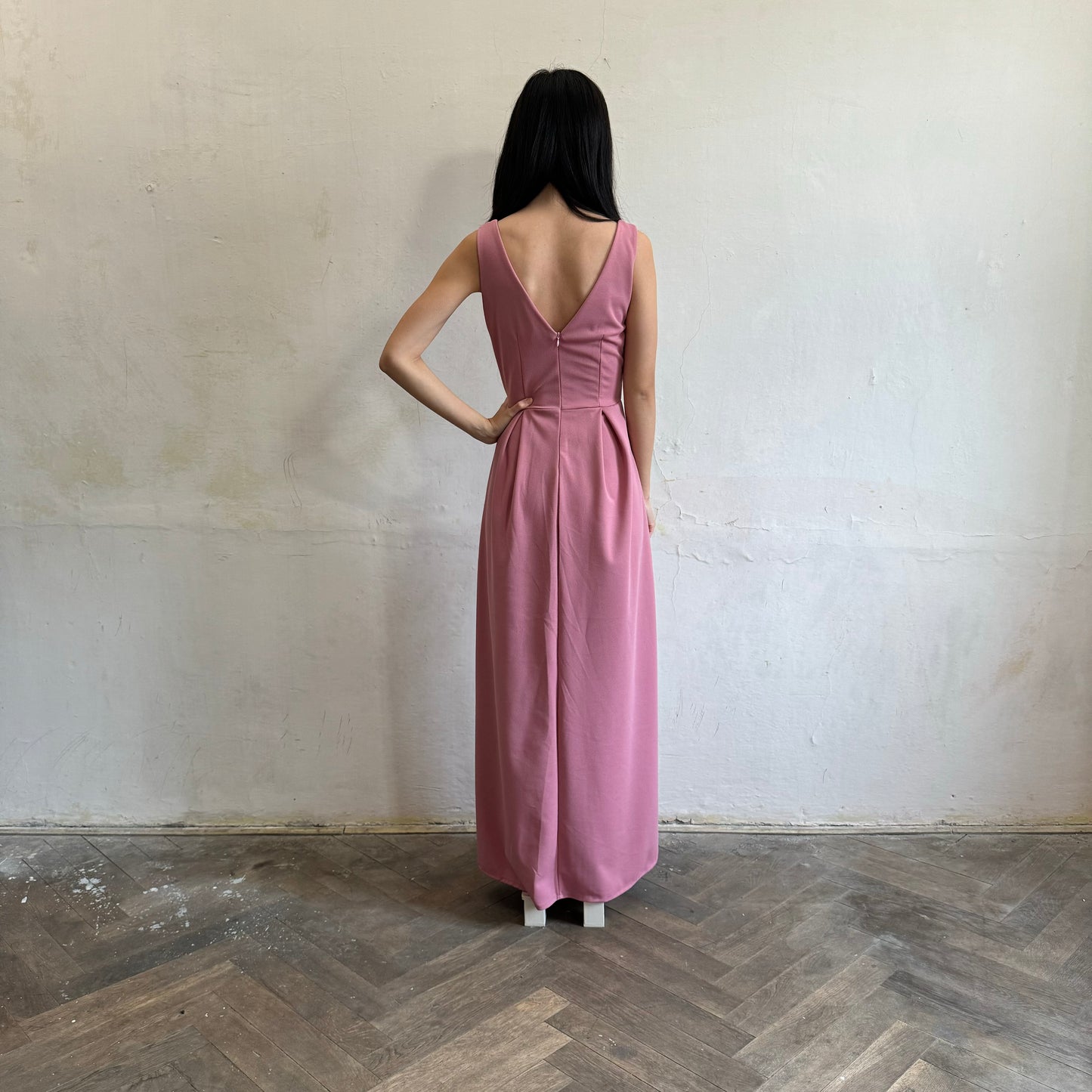 Modelka asijského původu pózující zezadu oblečená ve tmavě růžových společenských šatech s rozparkem