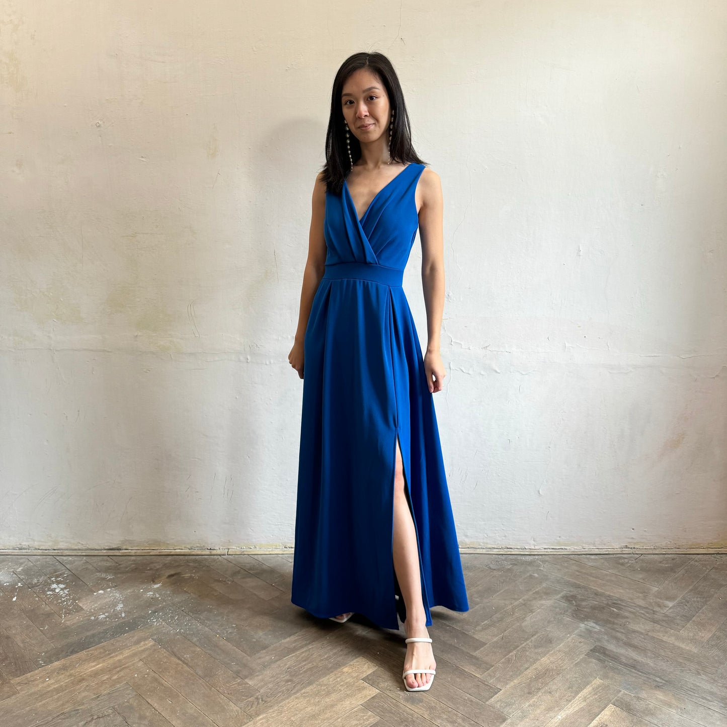 Modelka asijského původu pózující zepředu oblečená ve královsky modrých společenských šatech s rozparkem