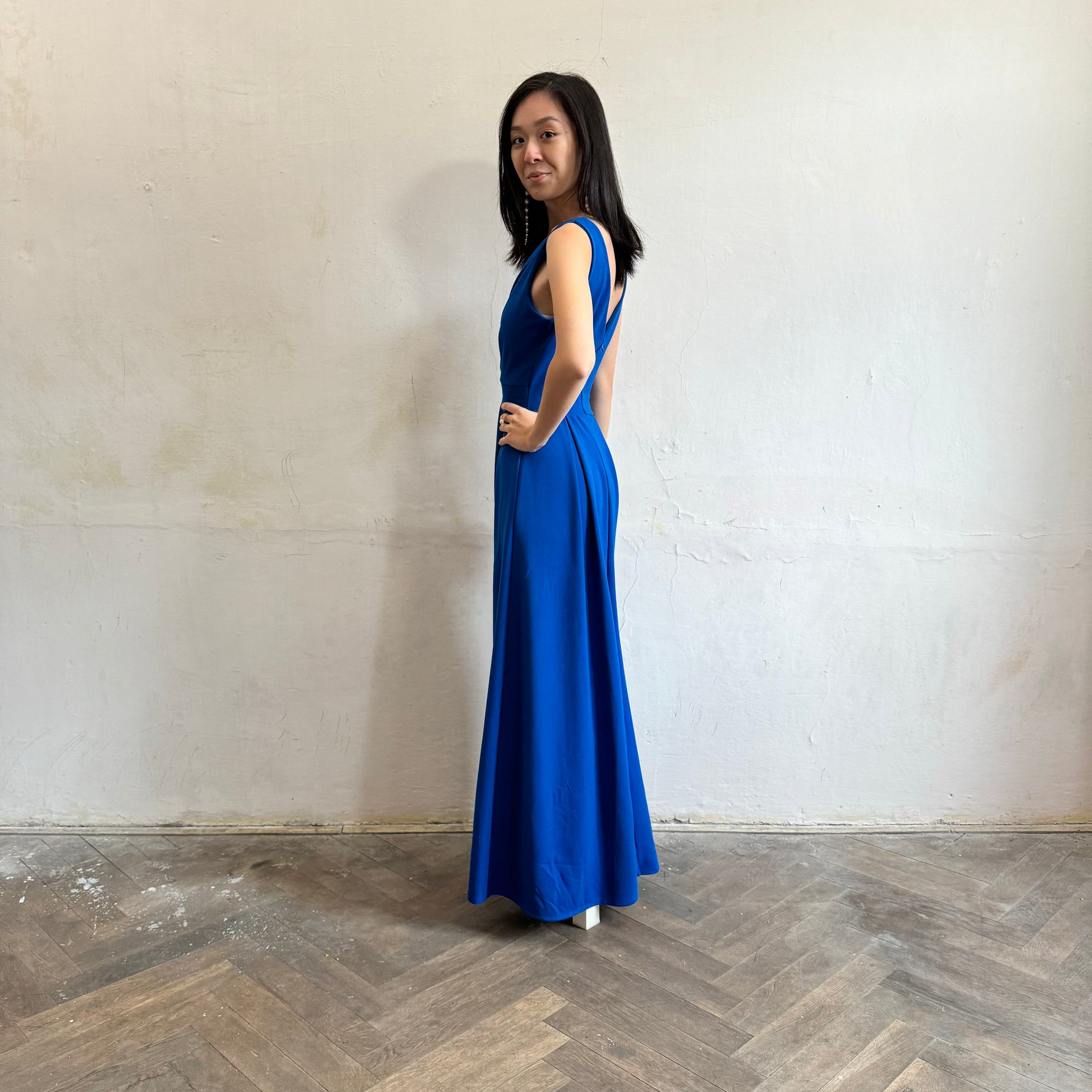 Modelka asijského původu pózující z boku oblečená ve královsky modrých společenských šatech s rozparkem