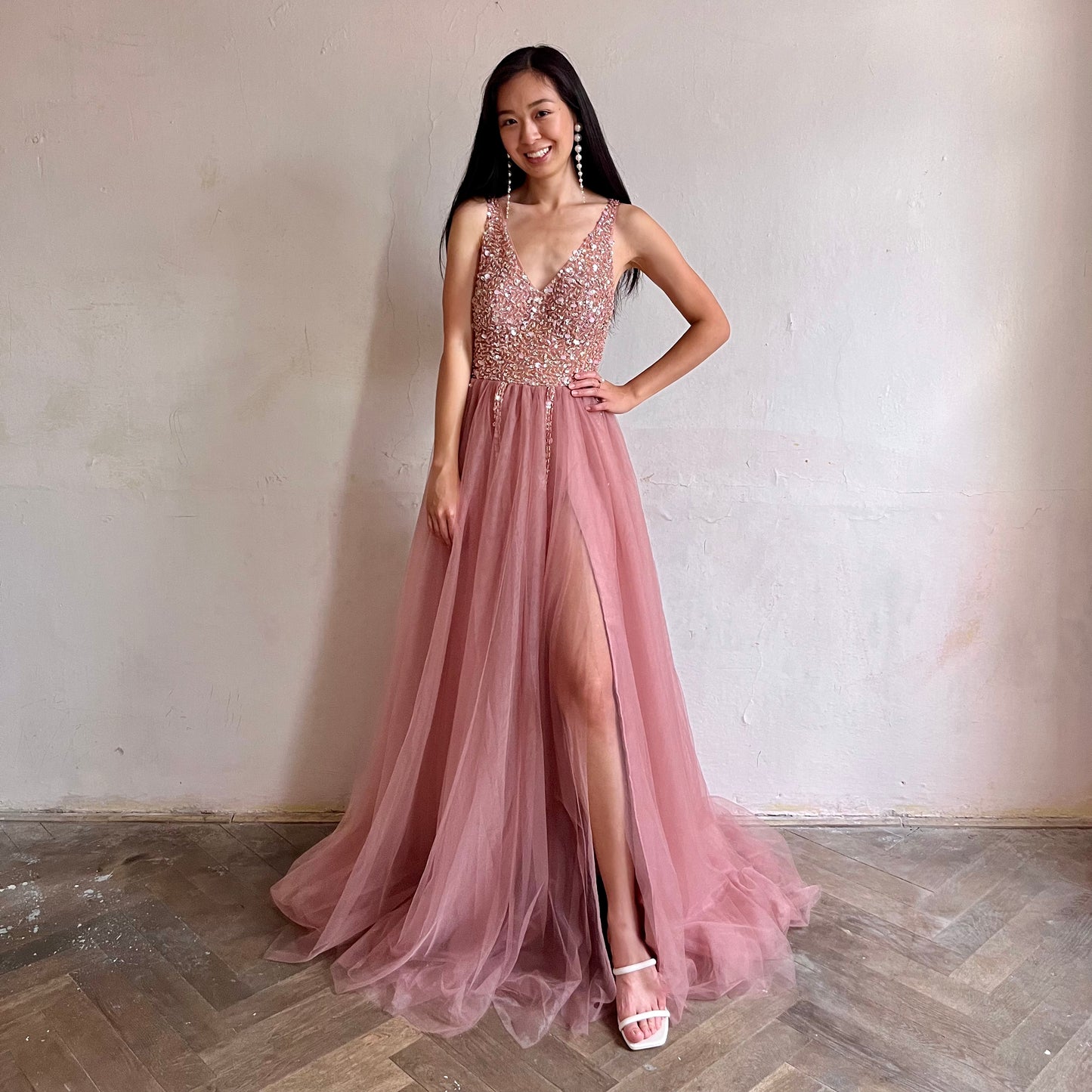 Modelka asijského původu pózující zepředu oblečená v dlouhých růžových plesových šatech 