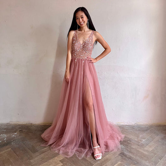 Modelka asijského původu pózující zepředu oblečená v dlouhých růžových plesových šatech 