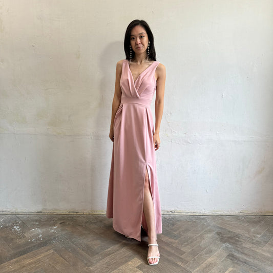 Modelka asijského původu pózující zepředu oblečená ve světle růžových společenských šatech s rozparkem