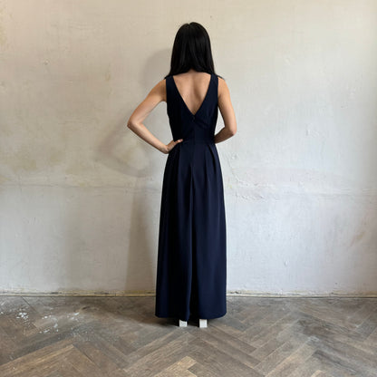 Modelka asijského původu pózující zezadu oblečená v tmavě modrých společenských šatech s rozparkem
