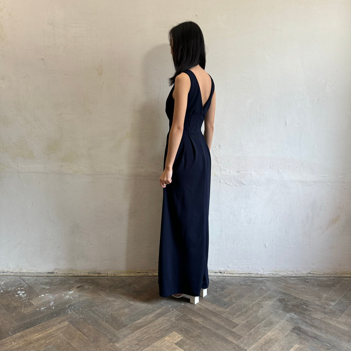 Modelka asijského původu pózující z boku oblečená v tmavě modrých společenských šatech s rozparkem