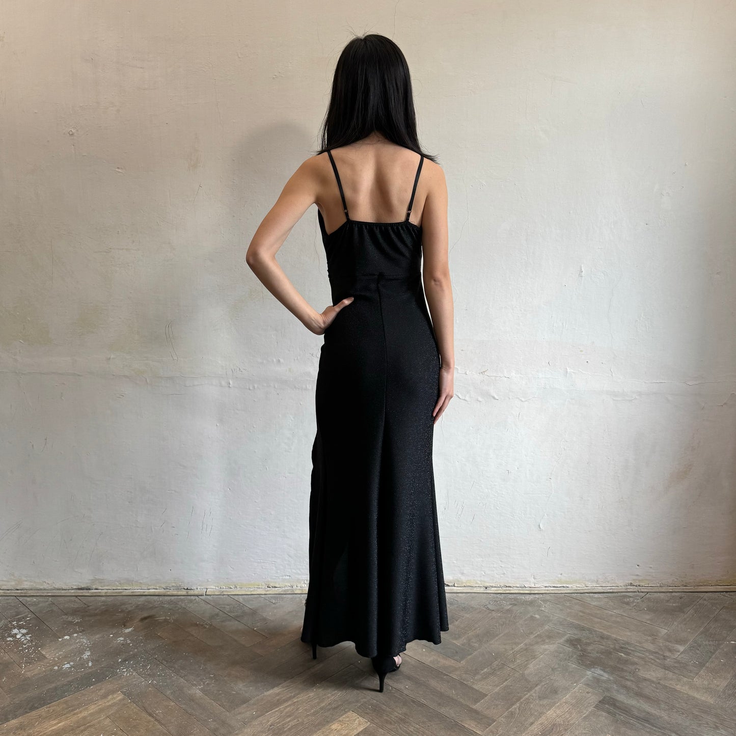 Modelka asijského původu pózující zezadu se třpytivými společenskými šaty v černé barvě