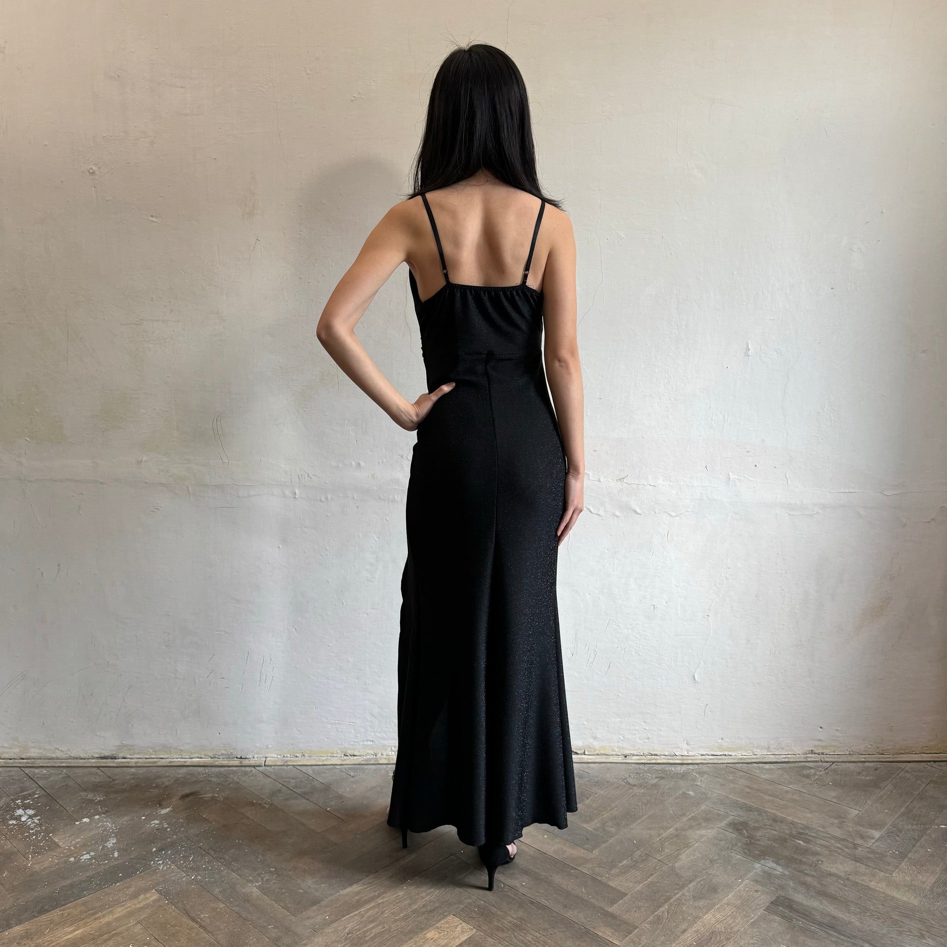 Modelka asijského původu pózující zezadu se třpytivými společenskými šaty v černé barvě