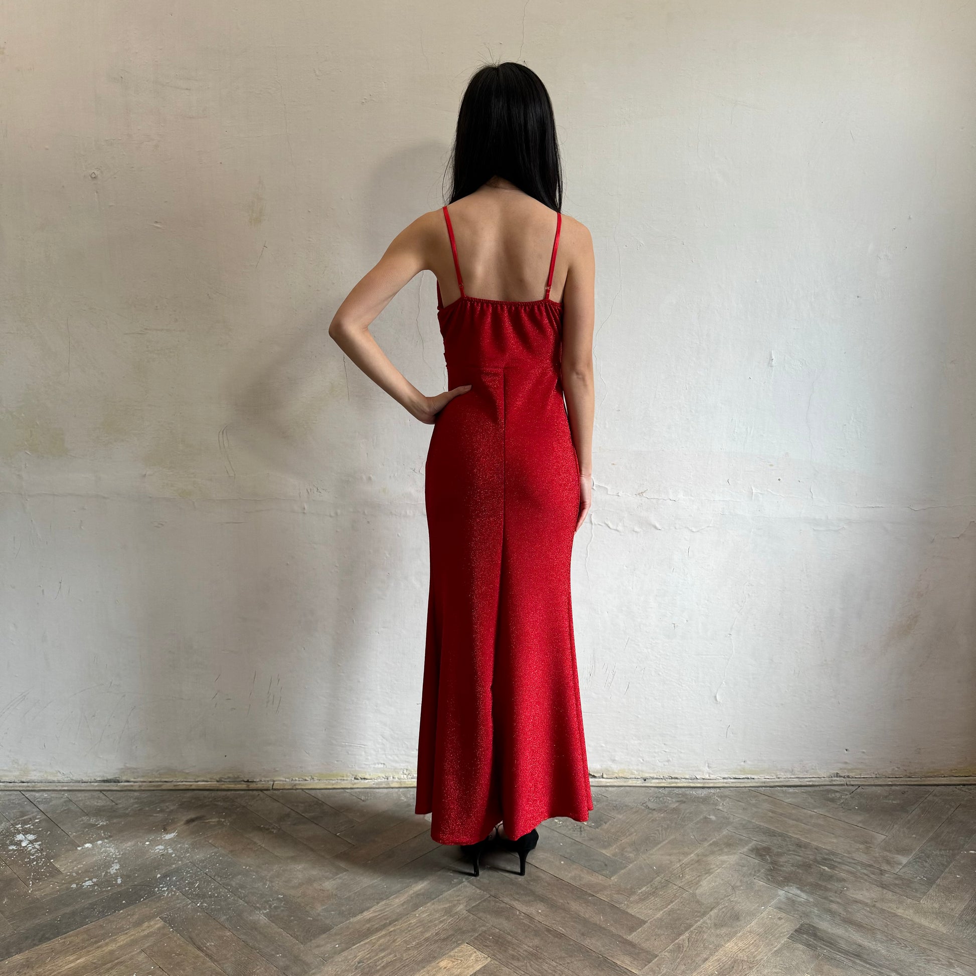 Modelka asijského původu pózující zezadu se třpytivými společenskými šaty v červené barvě