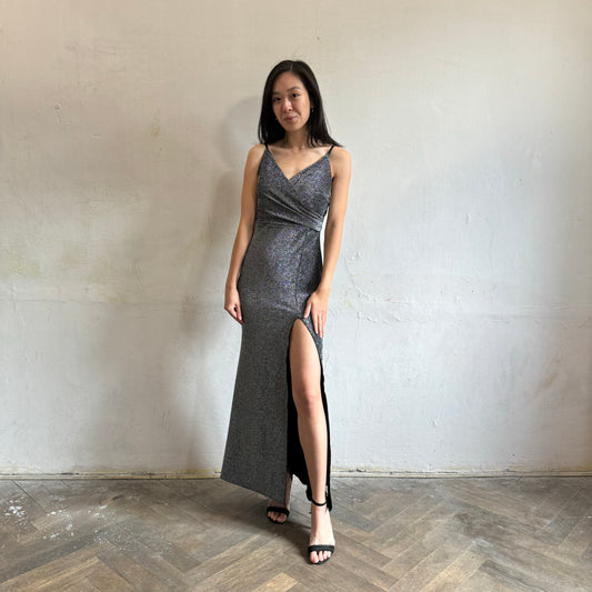 Modelka asijského původu pózující zepředu se třpytivými společenskými šaty ve stříbrné barvě