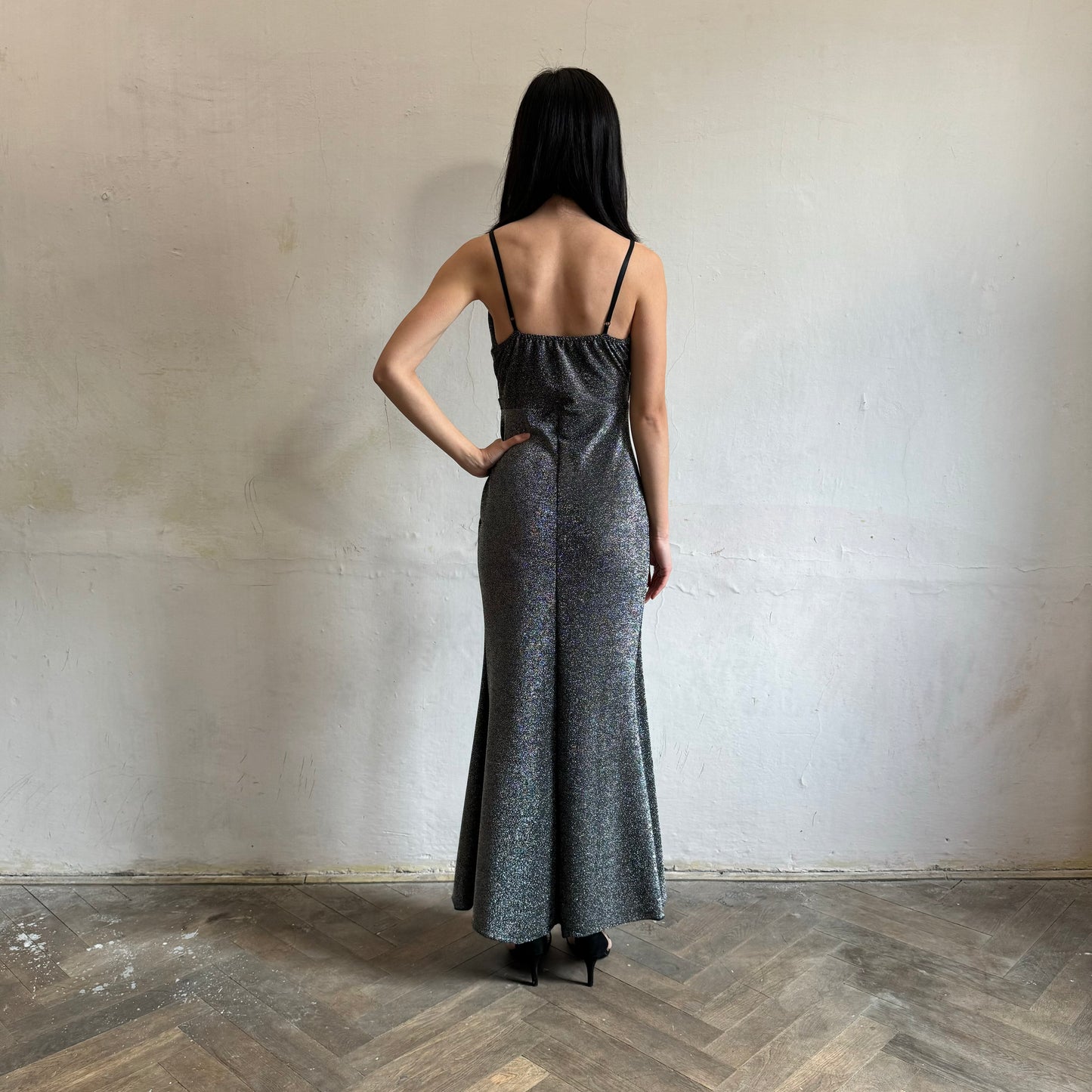 Modelka asijského původu pózující zezadu se třpytivými společenskými šaty ve stříbrné barvě