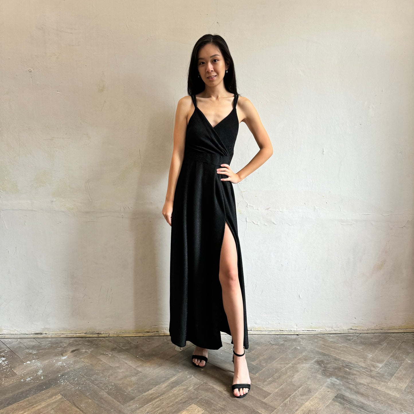 Modelka asijského původu pózující zepředu se třpytivými společenskými šaty v černé barvě
