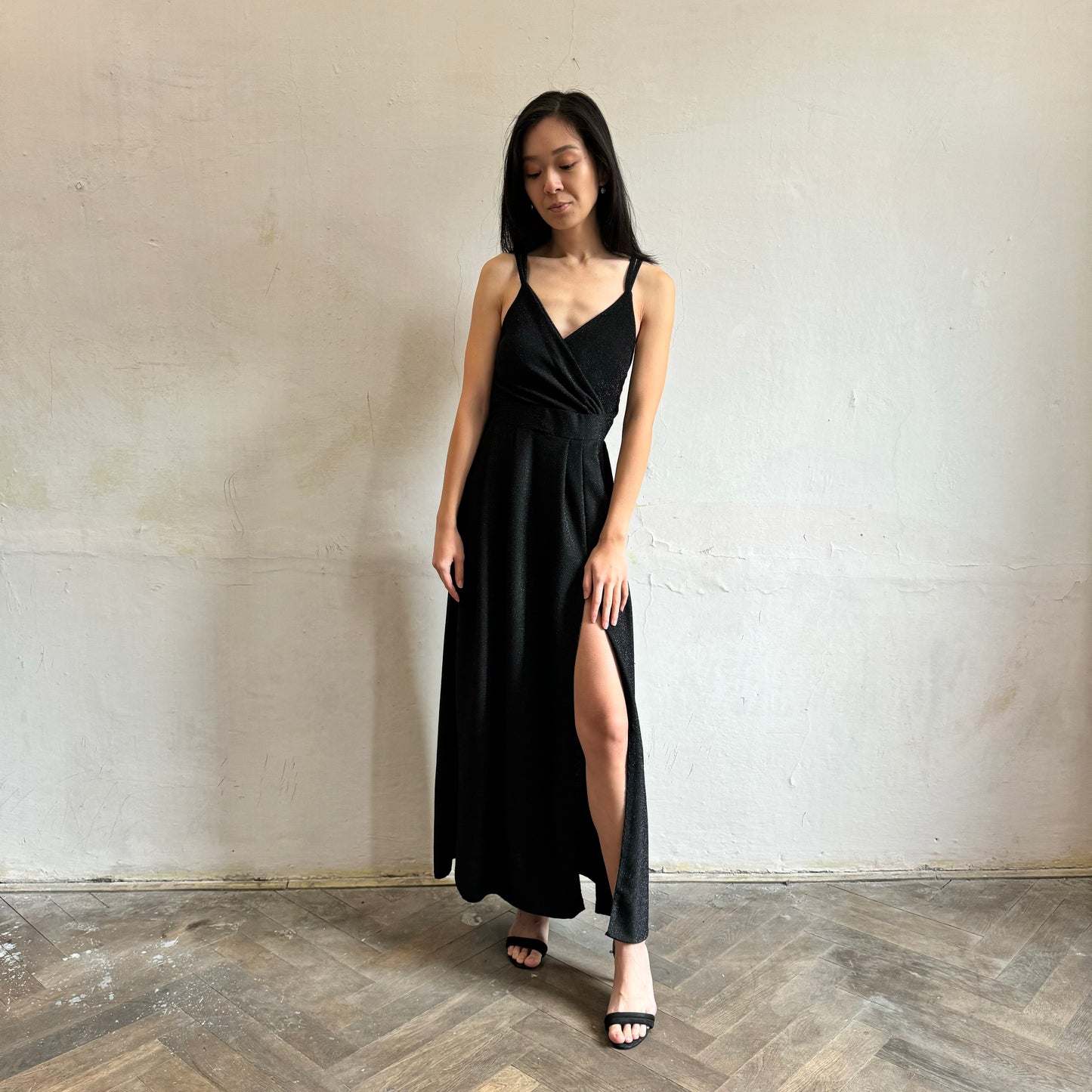 Modelka asijského původu pózující zepředu se třpytivými společenskými šaty v černé barvě