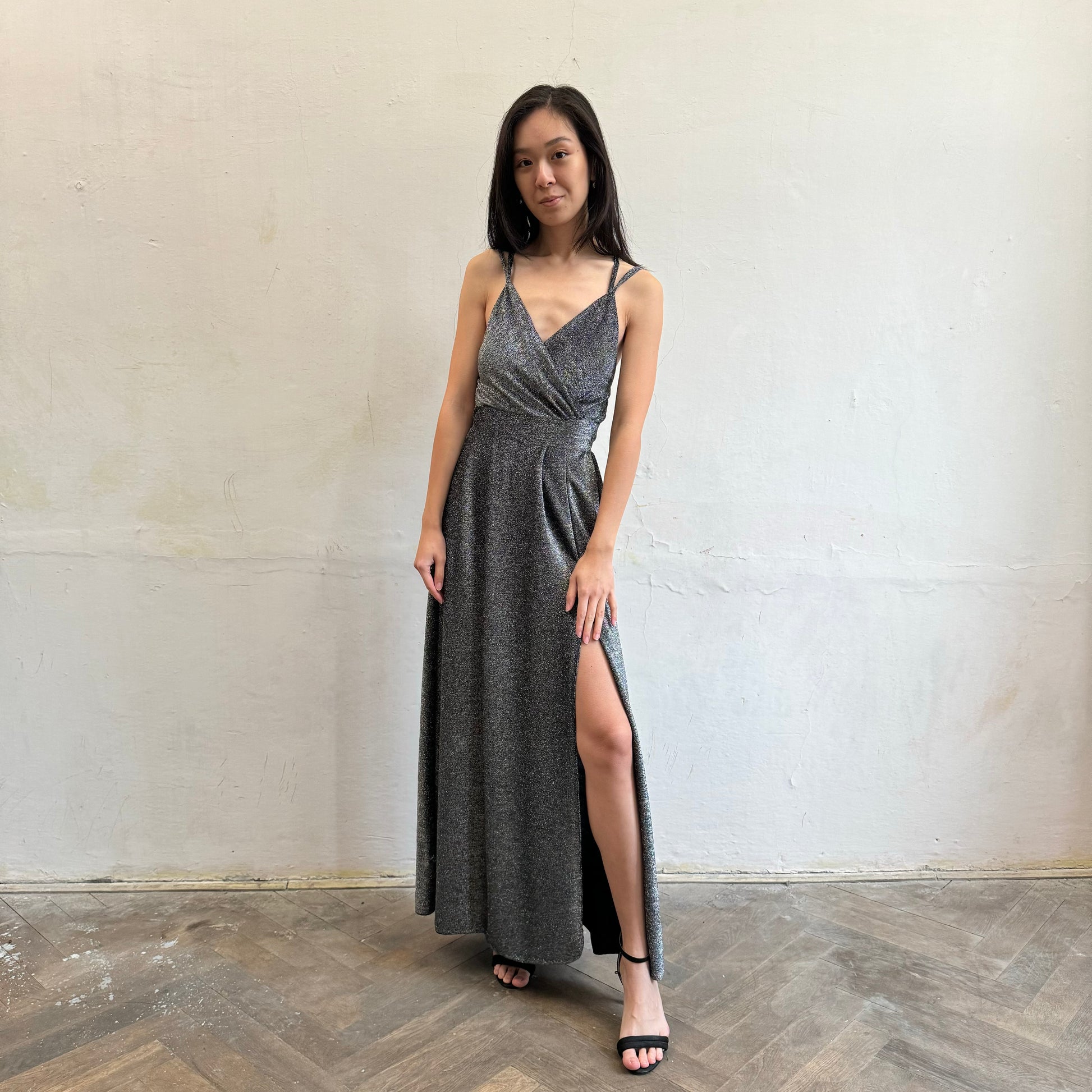 Modelka asijského původu pózující zepředu se třpytivými společenskými šaty ve stříbrné barvě