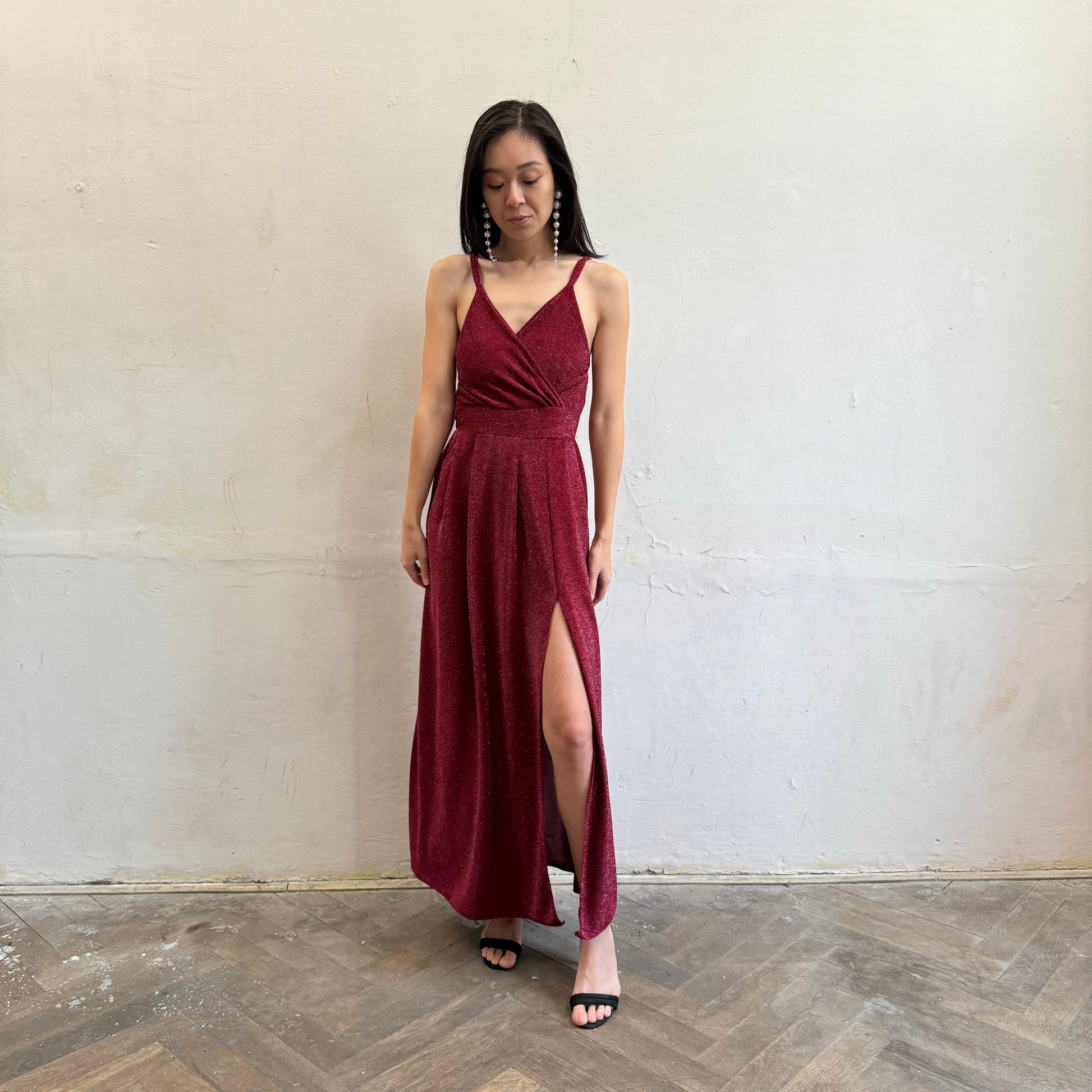 Modelka asijského původu pózující zepředu se třpytivými společenskými šaty ve vínové barvě